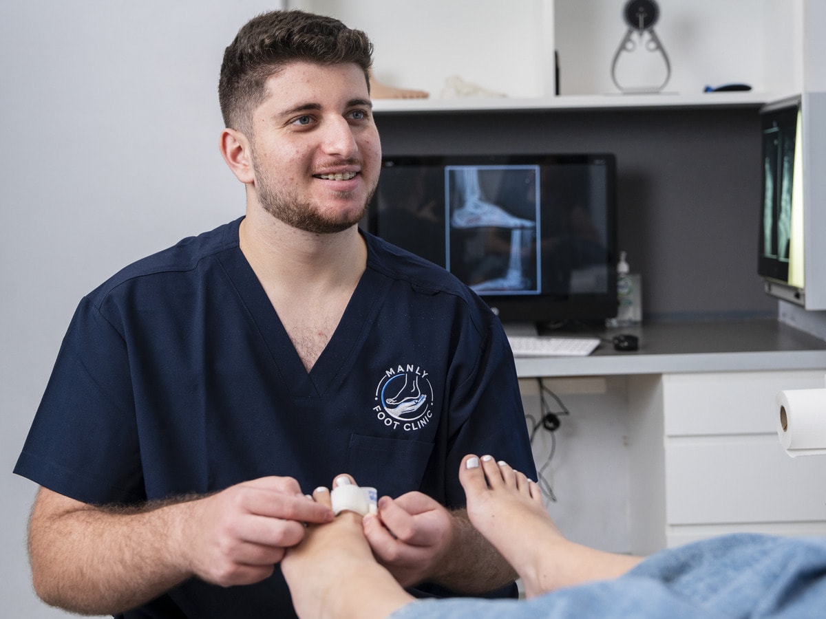 A podiatrist strapping a patient’s toe at Manly Foot Clinic